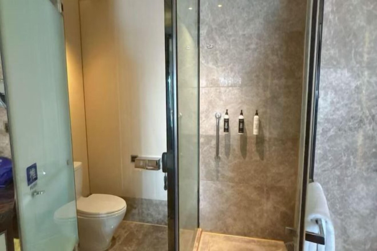 A bathroom with a glass shower enclosure, a toilet, and a sink.