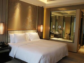 A hotel room with a large bed, bedside lamps, a mirror, and a view of the bathroom. - Wanda Realm Fuyang (Fuyang)
