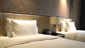 Habitació d'hotel amb dos llits, una làmpada penjada a la paret i un telèfon a la tauleta de nit.