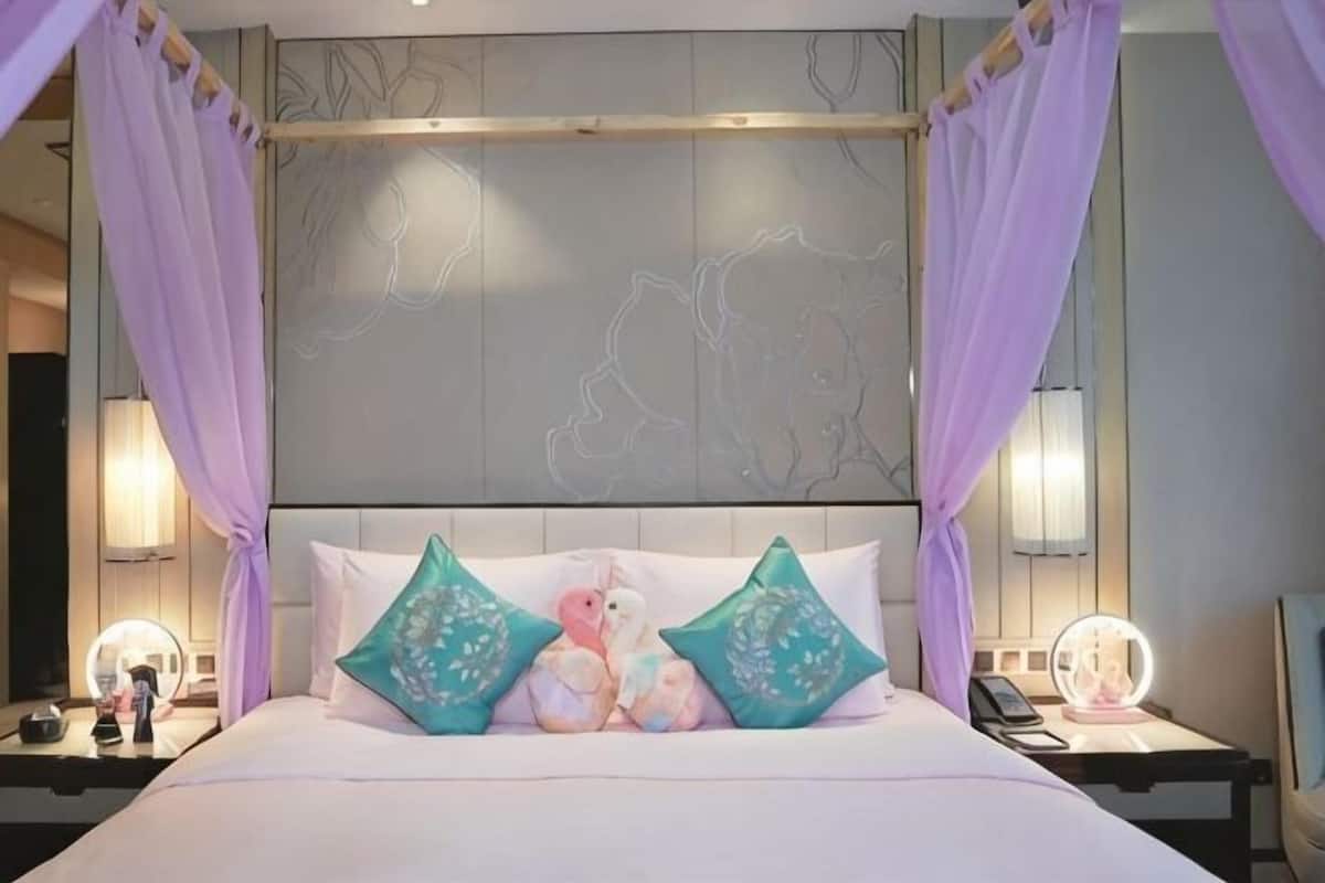 A bed with a canopy, two bedside tables with lamps, and a headboard with a decorative panel.