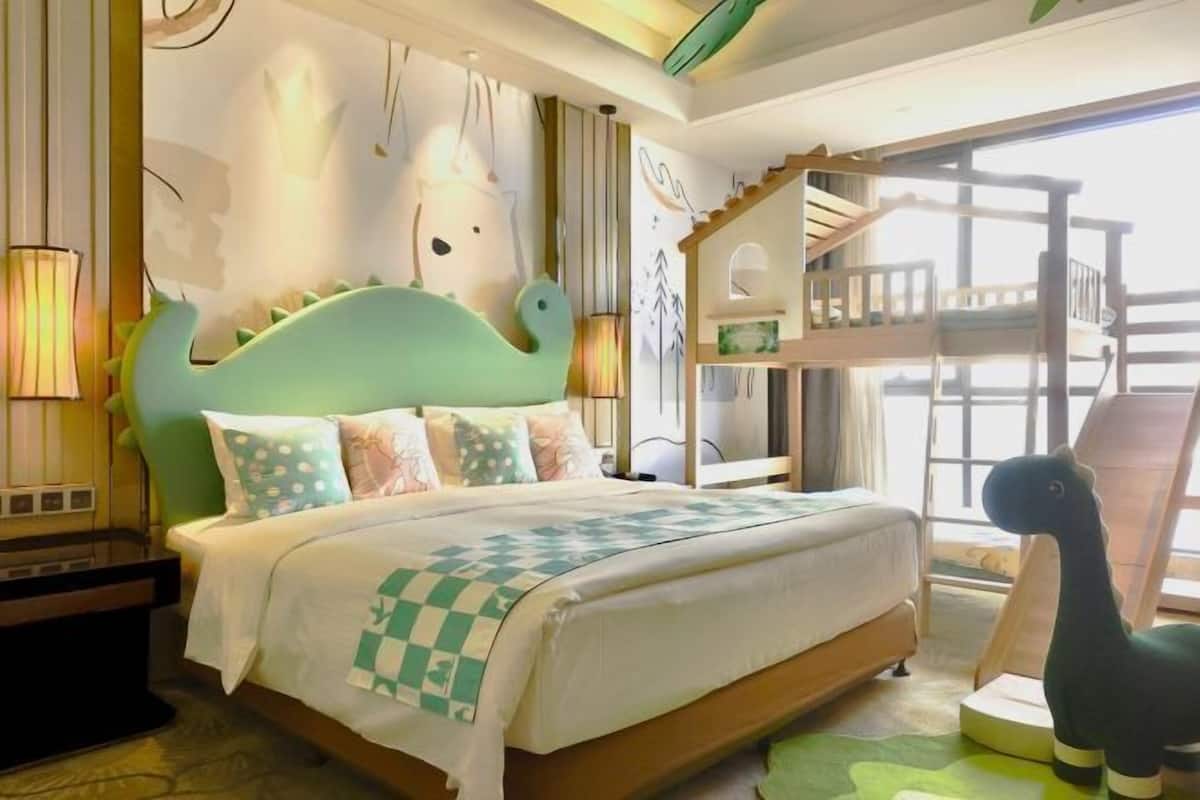 A bedroom with a bed, a nightstand, a lamp, a window, and a bunk bed.