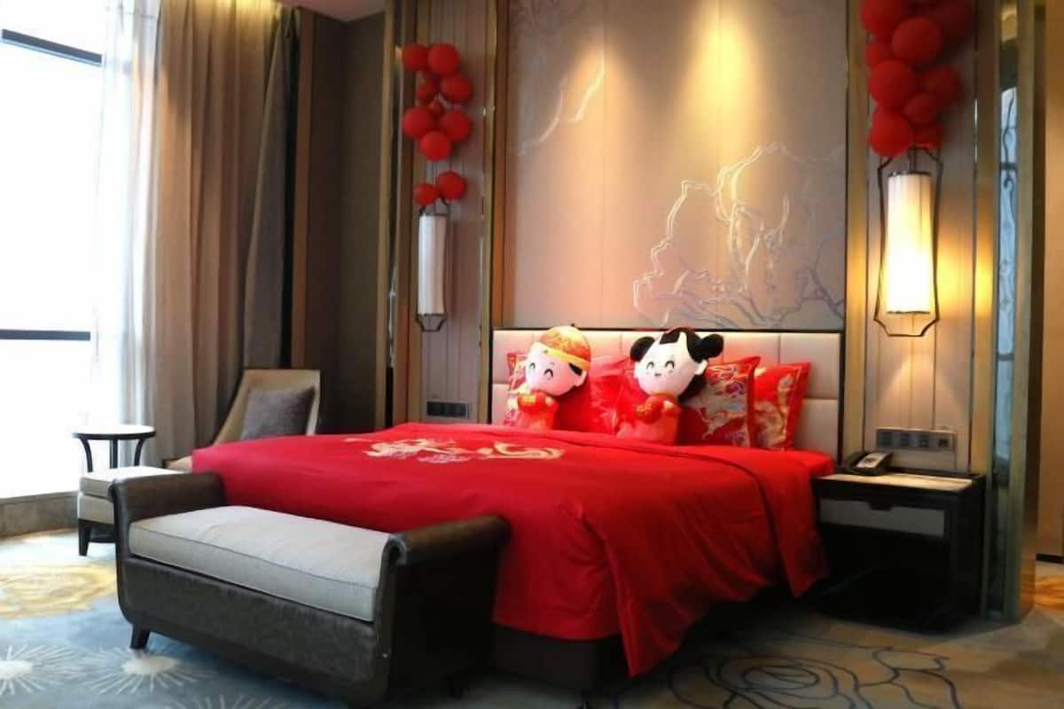 A hotel room with a bed, a nightstand, a chair, and a large window.
