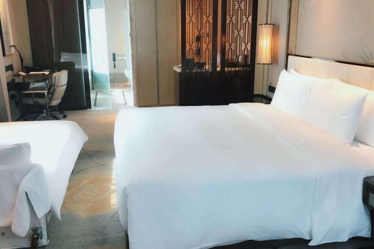 A hotel room with a large bed, a desk, and a chair.