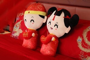 Two plush toys on a red bedspread with embroidered designs. - Wanda Realm Fuyang (Fuyang)