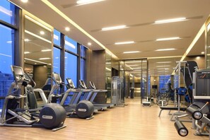 A gym with cardio equipment, weight machines, and mirrors on the walls.
