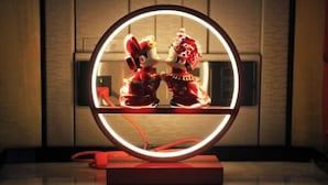 A circular mirror with a red frame, reflecting two figures in traditional attire. - Wanda Realm Fuyang (Fuyang)