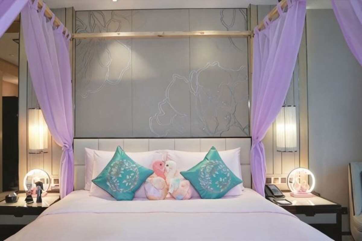 A bed with a canopy, two bedside tables with lamps, and a headboard with a decorative panel.