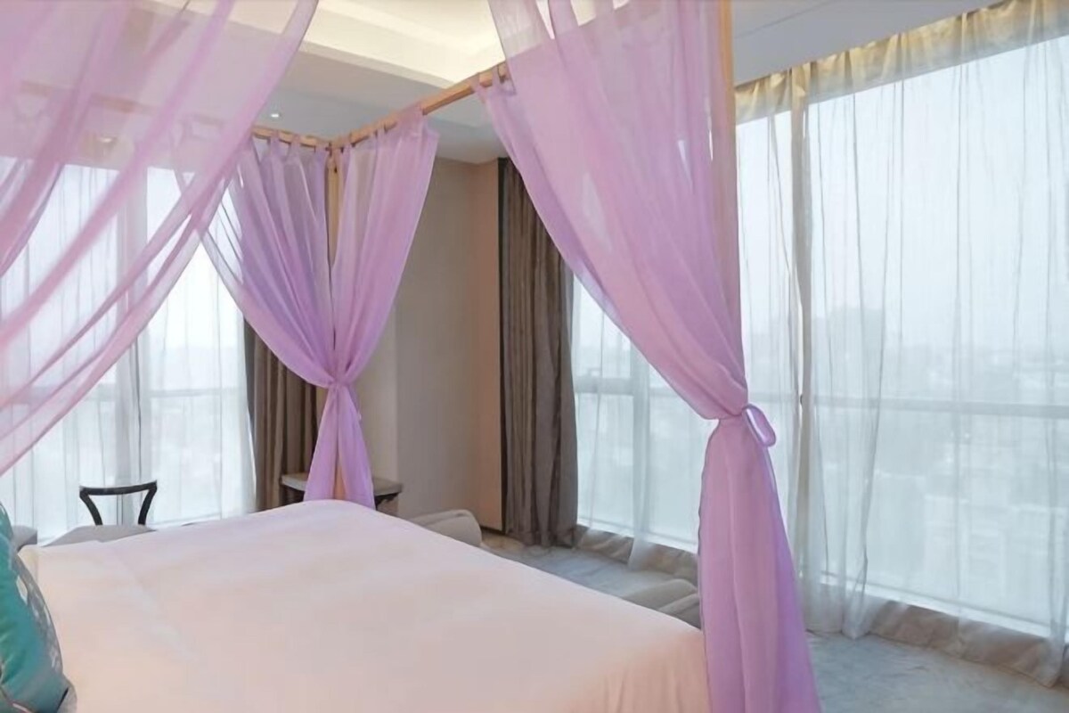 A bedroom with a bed, a chair, and a window with curtains.