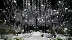 A banquet hall with tables set for a formal event, adorned with white flowers and a ceiling of hanging lights. - Wanda Realm Fuyang (Fuyang)