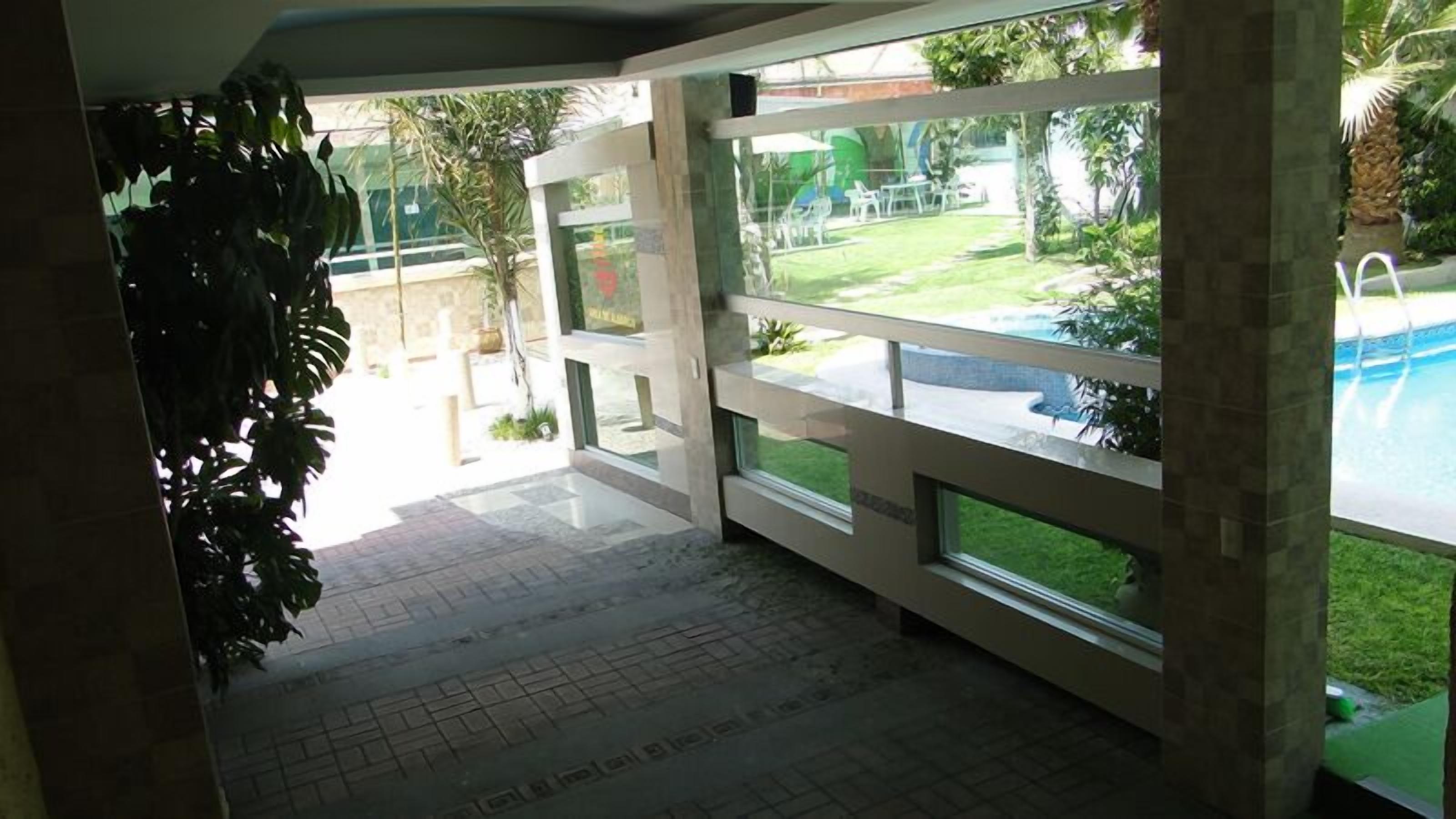 Una habitación con grandes ventanales que dan a una piscina y un área verde.
