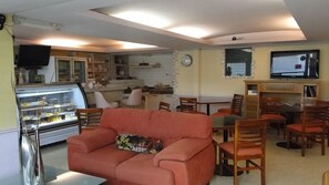A living room with a sofa, dining area with chairs, a kitchen area with a refrigerator, and a television mounted on the wall. - Hotel Cuellar (Tula de Allende)