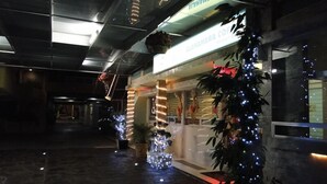 A corridor with a coffee shop named "ALAMBRA COFFEE" on the right, decorated with Christmas lights and a large artificial tree. - Hotel Cuellar (Tula de Allende)