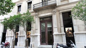 A building with a classical facade, large windows, and a prominent entrance with a dark door. - The Boutique Apartments (Barcelona)