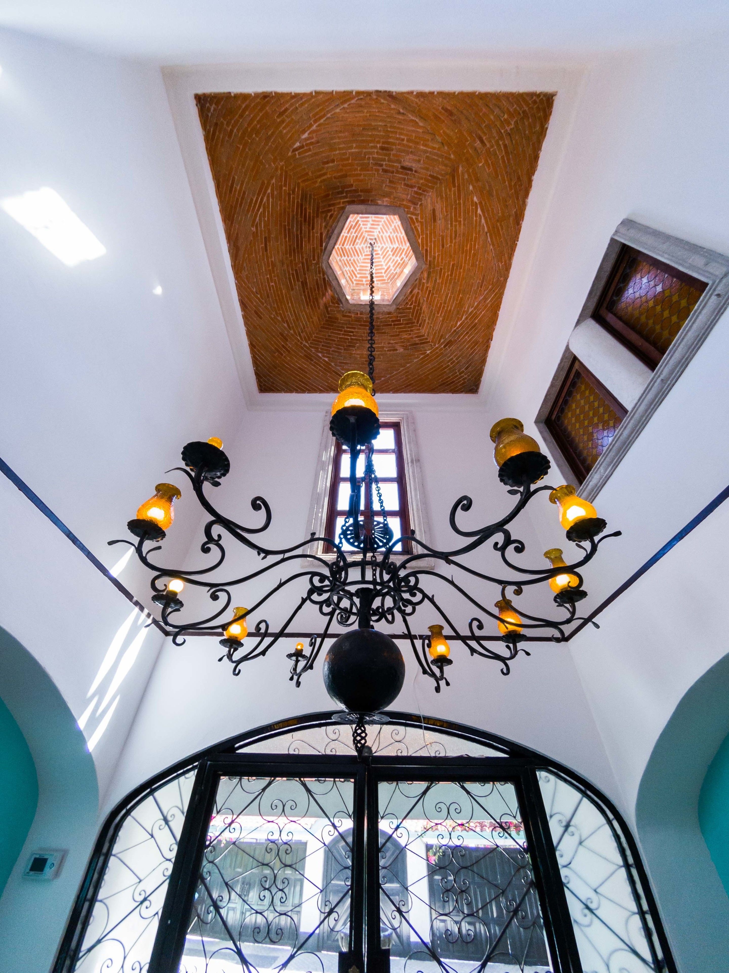 A chandelier with multiple light fixtures, a wooden ceiling, and a view of the outside through a window.