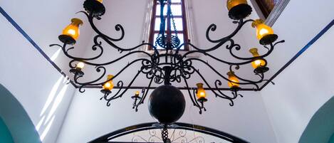A chandelier with multiple light fixtures, a wooden ceiling, and a view of the outside through a window.