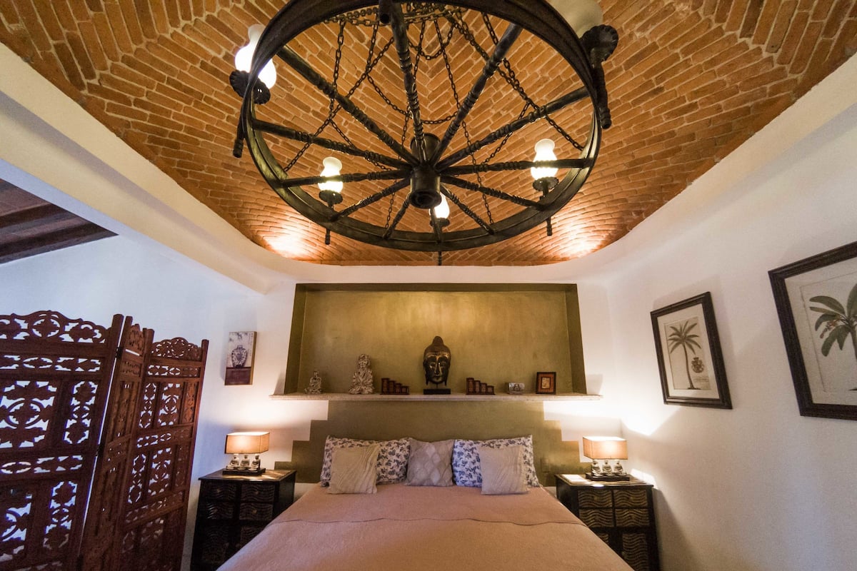 Ein Zimmer mit einem großen Bett, einer Holzbalkendecke und einem Wandregal mit Dekoration.