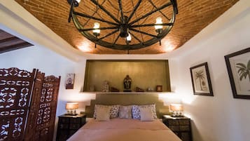 A room with a large bed, a wooden ceiling, and a wall-mounted shelf with decorative items.