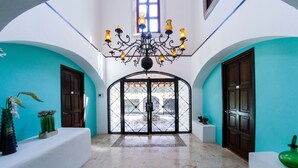 Ein geräumiger Flur mit Fliesenboden, einer dekorativen Chandelier und Blick durch eine Glastür nach draußen.