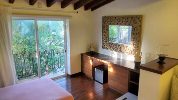 Una camera da letto con balcone, un letto, una cassettiera e uno specchio.