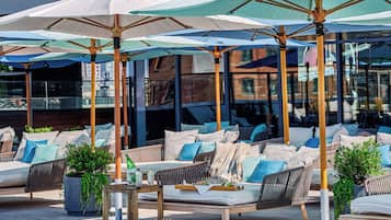 A poolside area with lounge chairs, umbrellas, and a pool.