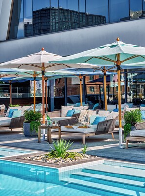 A poolside area with lounge chairs, umbrellas, and a pool. - The William Vale (Brooklyn)