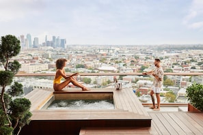 A couple on a rooftop terrace with a city view, a hot tub, and a potted plant. - The William Vale (Brooklyn)