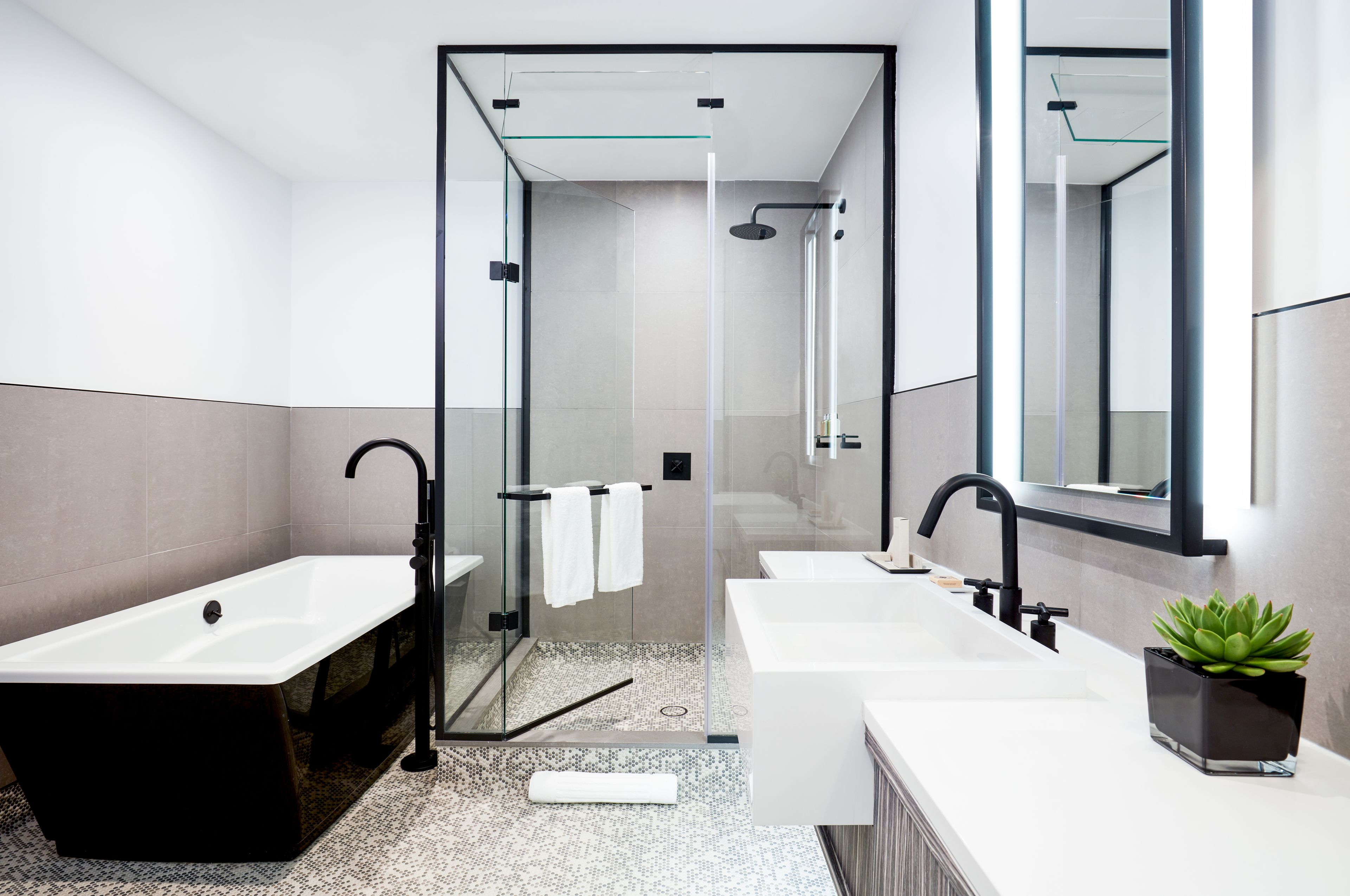 A modern bathroom with a glass-enclosed shower, a freestanding bathtub, and a vanity with a mirror.