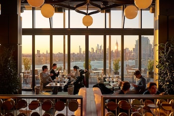 A cozy room with a fireplace, a Christmas tree, and a large window overlooking a cityscape. at The William Vale