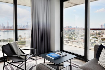 A gym with various exercise equipment, large windows, and a view of buildings outside. at The William Vale