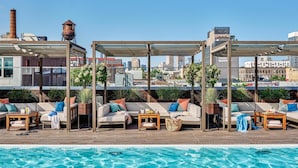 A rooftop pool area with seating arrangements and a view of the city skyline.