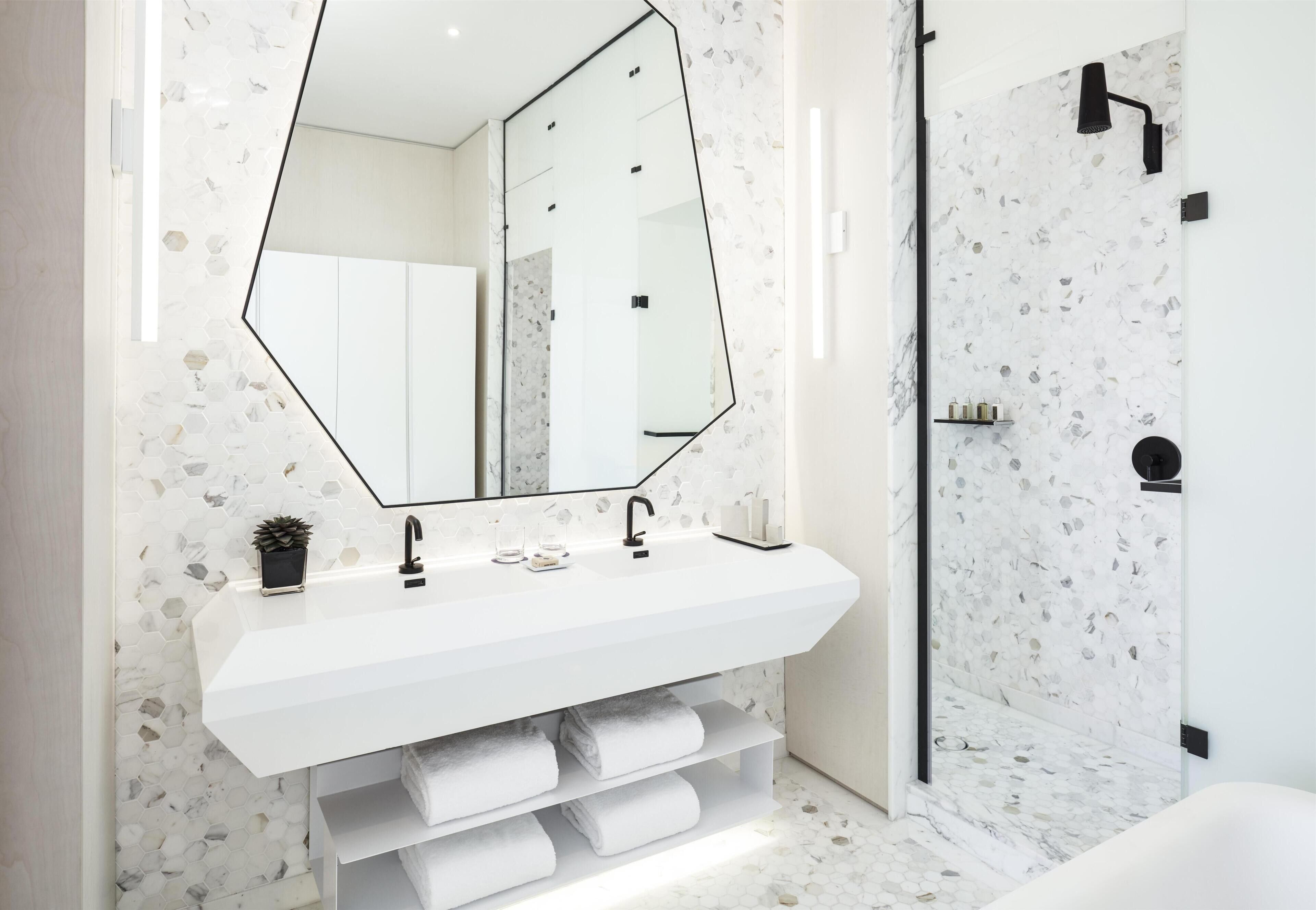 Une salle de bain moderne avec un lavabo blanc, un grand miroir et un espace douche.