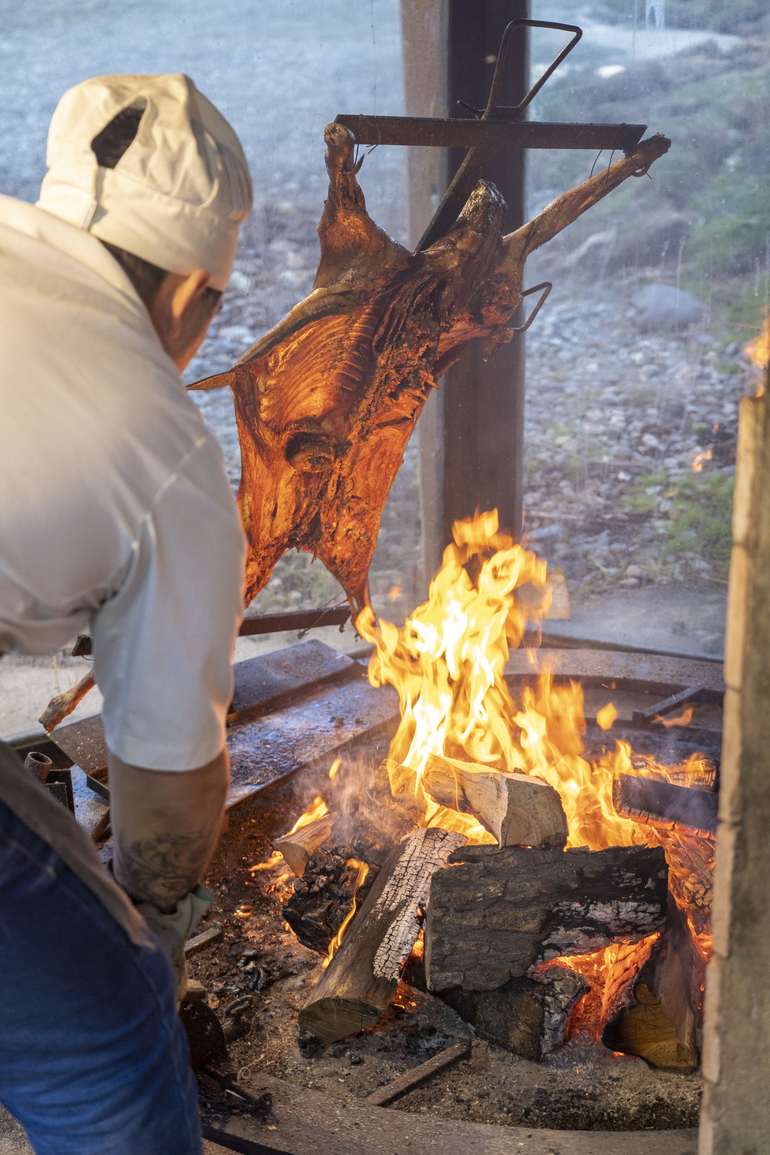 Una persona cuidando un gran brasero con leña y troncos ardiendo.