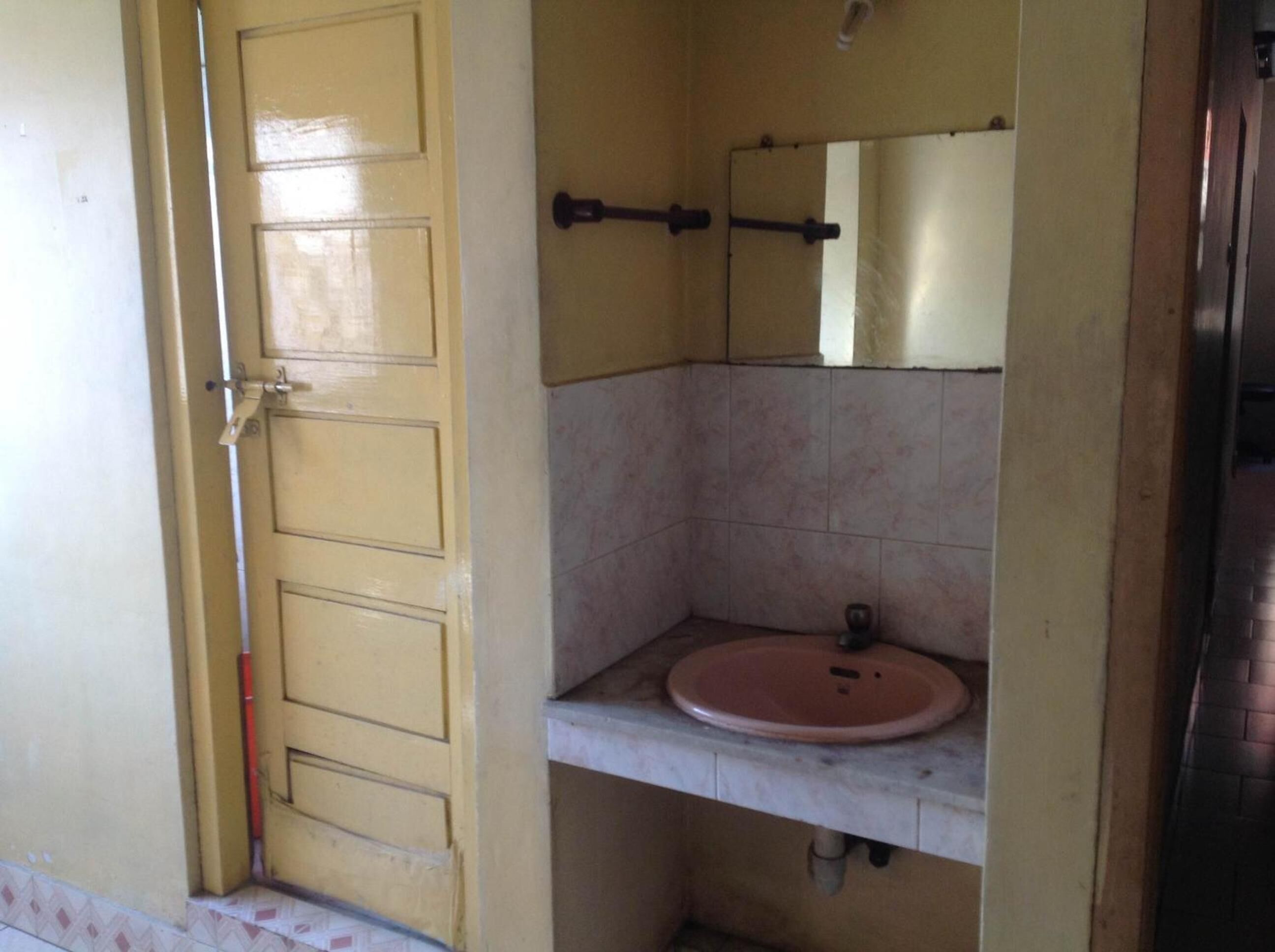 Une salle de bain avec une porte jaune, un lavabo et un miroir.