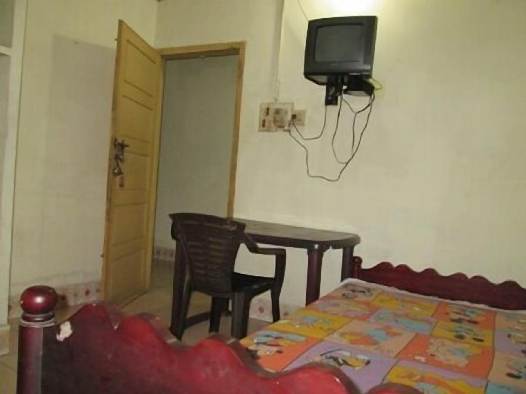 A room with a bed, a desk, and a television mounted on the wall.
