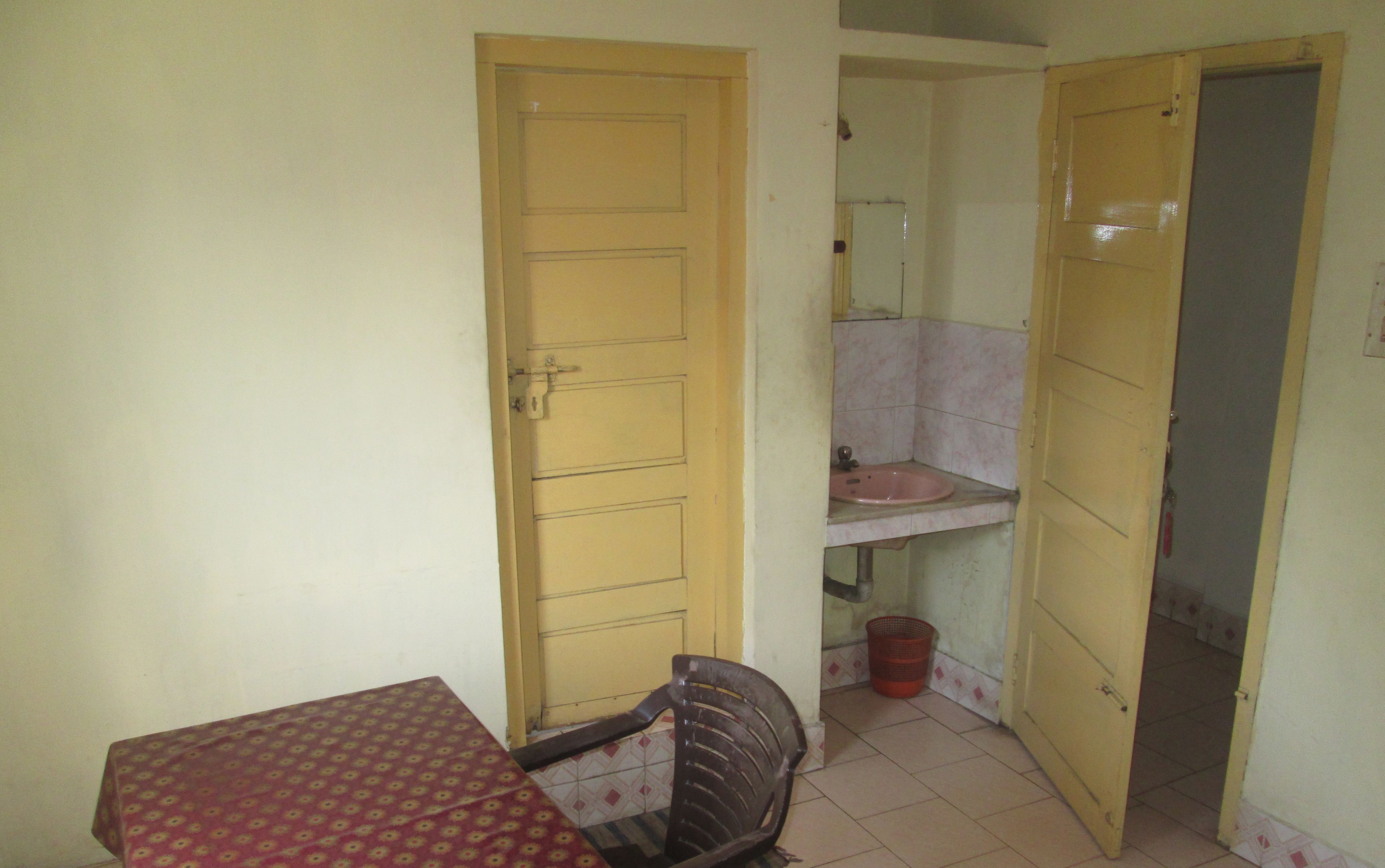 A small room with a table, a chair, a sink, and a door.