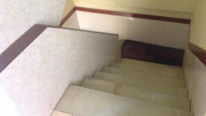 A staircase with a beige carpet and a dark-colored handrail, leading to a landing with a white wall and a red trim. - St.Antonys Lodge Ernakulam Market (Kanayannur)