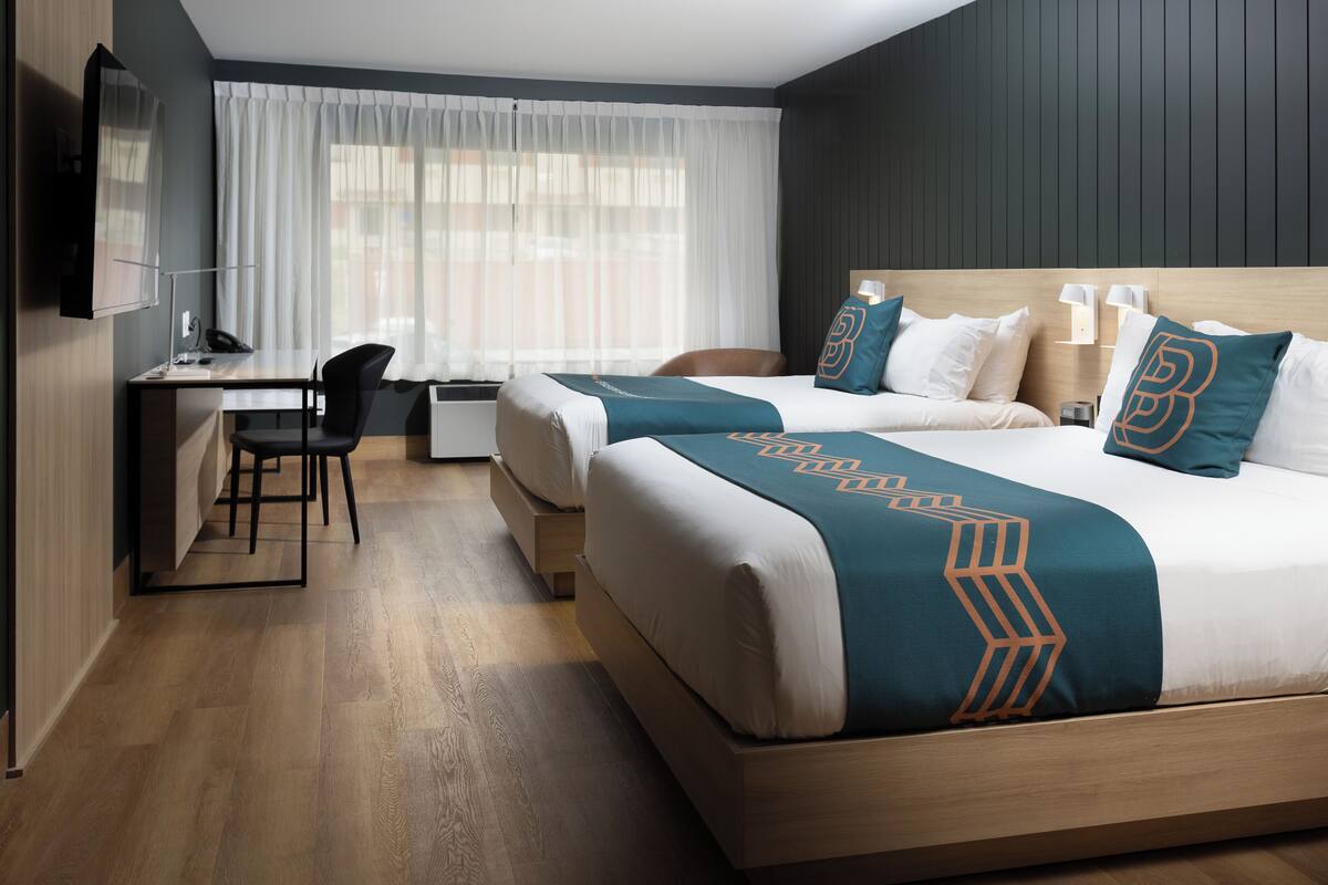 Ein Hotelzimmer mit zwei Betten, einem Schreibtisch und einem Fernseher.