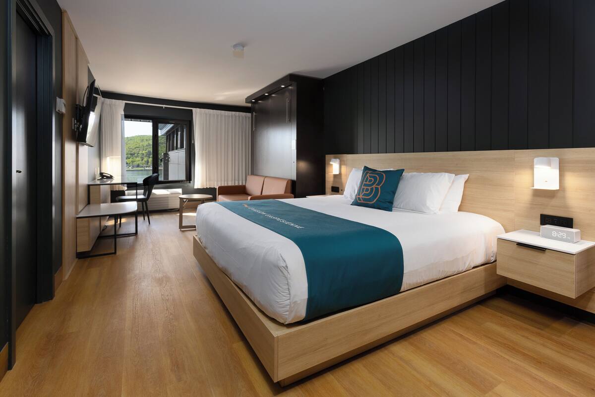 Ein modernes Hotelzimmer mit einem großen Bett, einem Schreibtisch und einem Sessel.