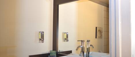 A modern bathroom with a large mirror, two sinks, and a towel rack.