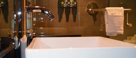 Ein modernes Badezimmer mit einem chromfarbenen Wasserhahn, einem weißen Waschbecken und einem Handtuchhalter.
