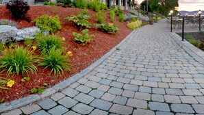 A paved pathway leading to outdoor seating with a view of a body of water. - Hôtel Baker (Gaspé)