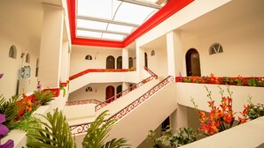 A multi-level interior with a central staircase, arched doorways, and a skylight. - Hotel El Español Centro Histórico (Mérida)