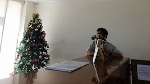 A room with a large ceiling mural, a Christmas tree, a desk with a computer, and a filing cabinet. - Hotel El Español Centro Histórico (Mérida)