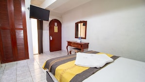 A hotel room with a bed, a wooden dresser, a mirror, and a television mounted on the wall. - Hotel El Español Centro Histórico (Mérida)