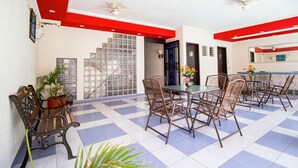 A dining area with a checkered floor, a central table with chairs, and a staircase in the background. - Hotel El Español Centro Histórico (Mérida)