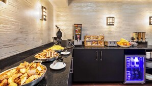 Disposição de buffet com diversos alimentos e uma geladeira.