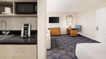 Una habitación de hotel con kitchenette, cama, televisión y baño.