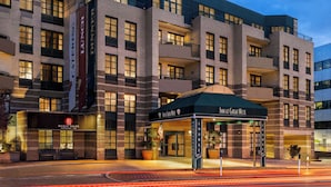 Um hotel com fachada de tijolos moderna, várias sacadas e uma entrada bem iluminada.