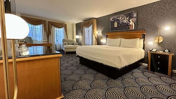 Habitación de hotel con una cama grande, un escritorio con espejo, una silla y una pared con diseño geométrico.