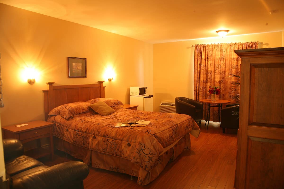 Habitación de hotel con una cama grande, un escritorio, una silla y una mesita.